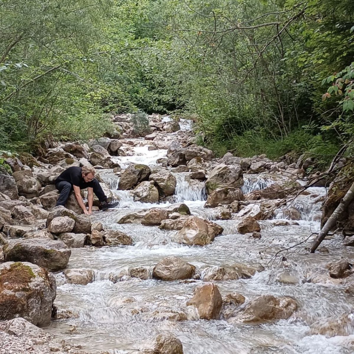 Julian washing his hands in a mountain stream.